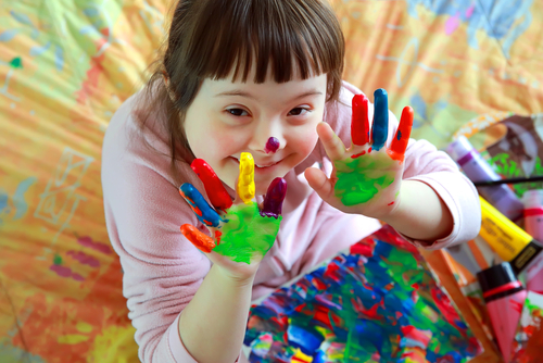 Girl with special educational needs playing with paint