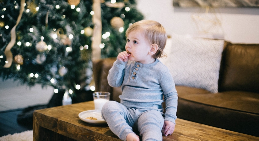 Baby having milk and cookies in front of a Christmas Tree
