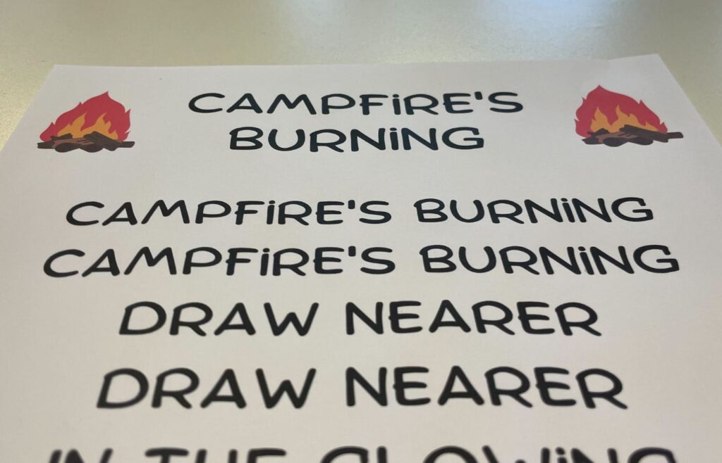 Photo of a sheet of paper. At the top is the title 'Campfire's burning' with two cartoon fires either side. Below the title are the lyrics to Campfire's burning.