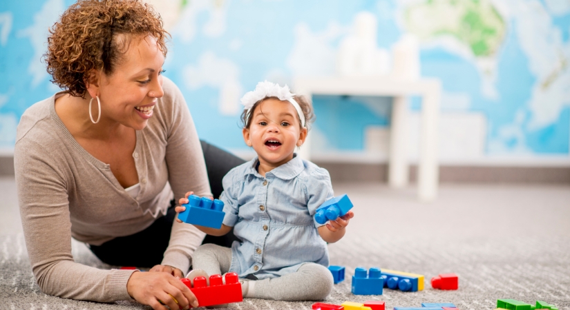 nursery practitioner observing a young child playing with building blocks